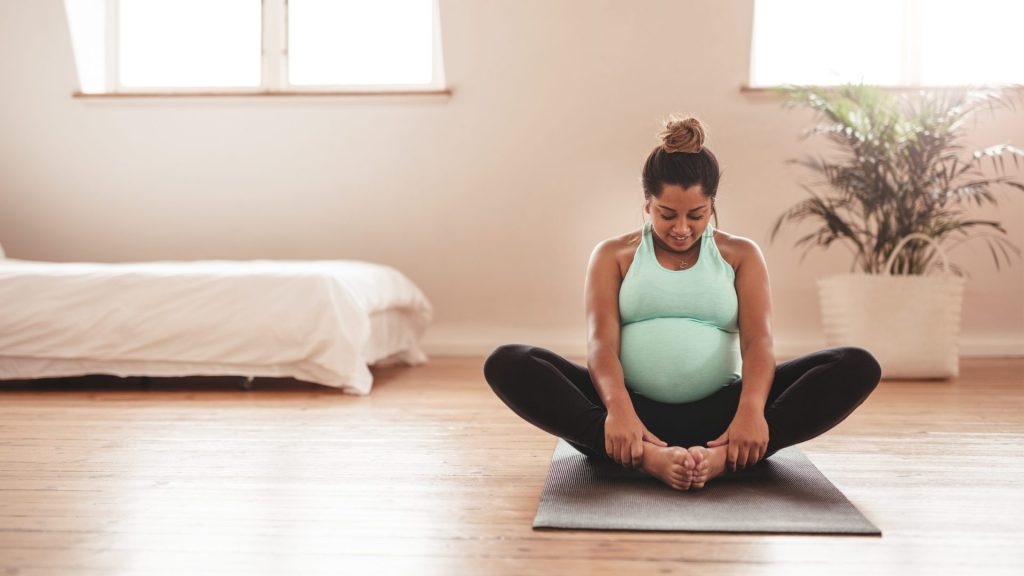 a pregnant woman sitting on a yoga mat