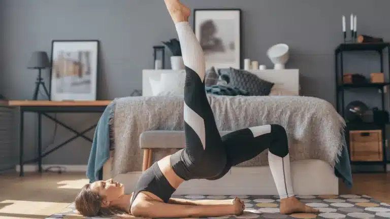 Woman performing single leg glute bridge on mat with one leg lifted and hips raised