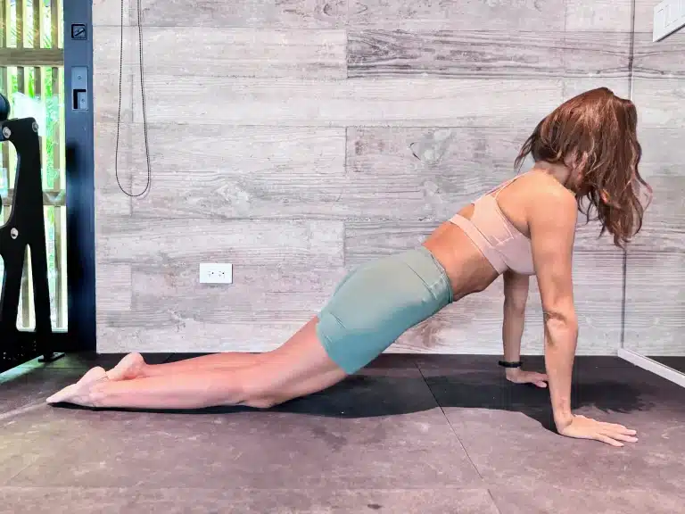 Woman holding forearm plank on knees with core engaged and spine neutral. Deep core exercises